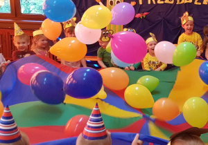 Zabawa z chustą animacyjną i kolorowymi balonikami – dzieci poruszają chustą animacyjną, wprawiając w ruch znajdujące się na niej baloniki.